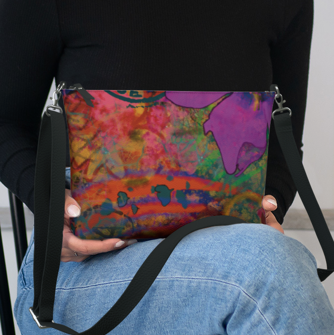 Person holding a colorful bag with a black strap, sitting on a black chair.