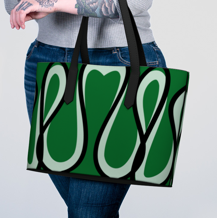 Person holding a green tote bag with abstract design on a plain background