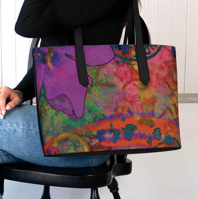 Person holding a colorful tote bag with abstract design, sitting on a chair.