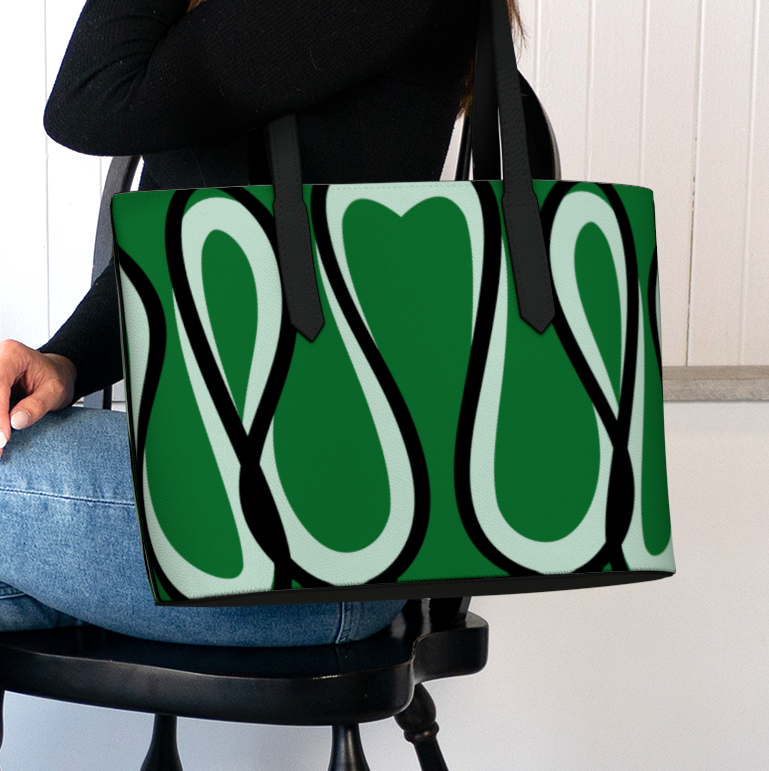 Person holding a green tote bag with abstract design in a room with plants and candles.